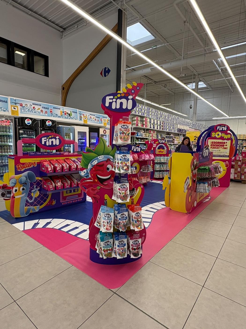 Isla de marca Fini en Carrefour con torre central de cartón y producto colgado en ganchos de metal