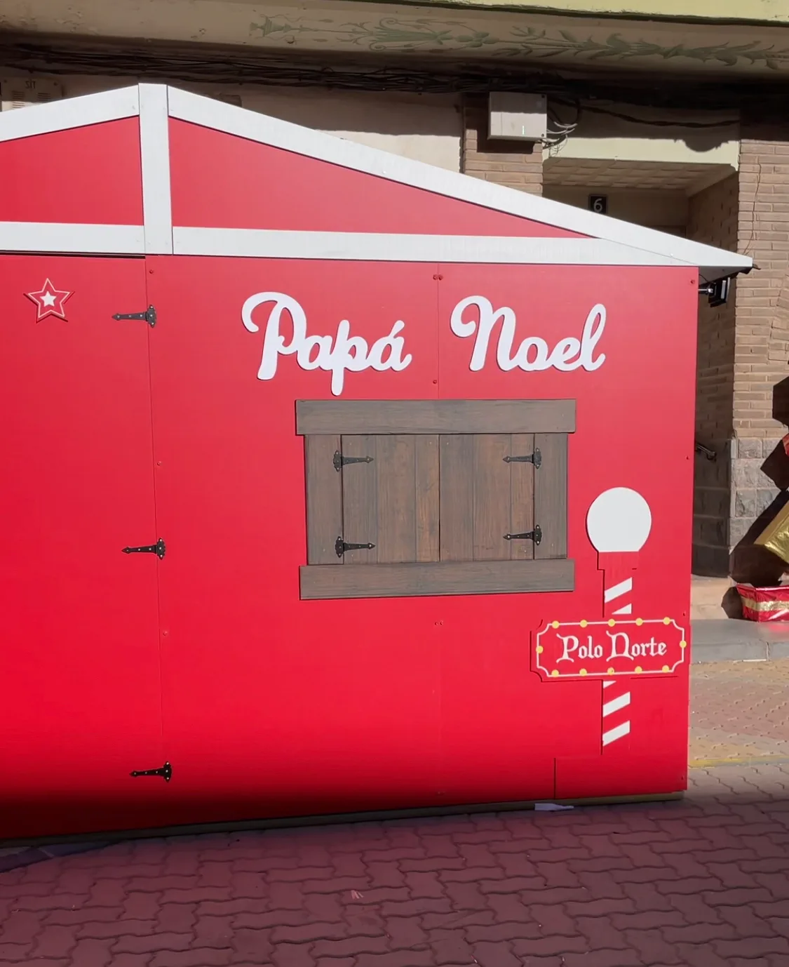 Fachada roja de la casa de Papá Noel en la Plaza de España de Illueca, con ventana de madera y cartel «Polo Norte»